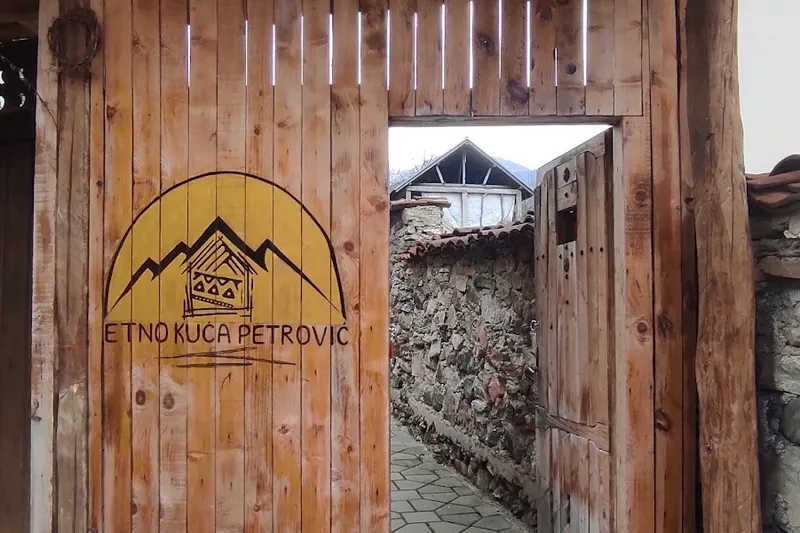 The wooden gate of Etno kuća Petrović with the house sign of mountains and a small house