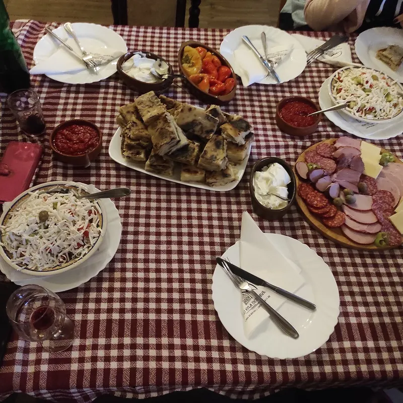 A table spread with cured meats, cheese, salads, pies and homemade dips on a gingham cloth