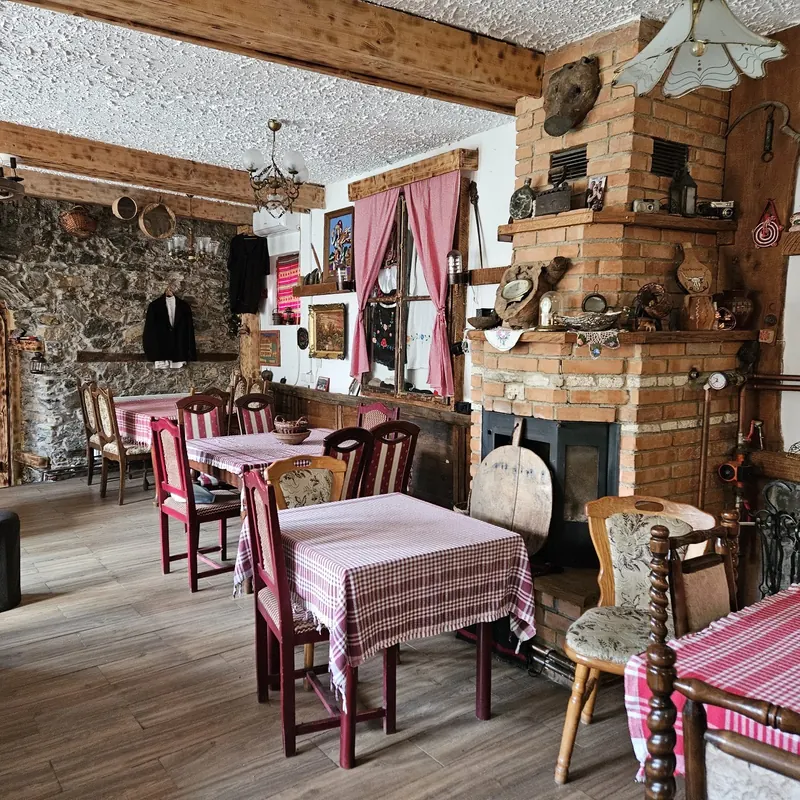 The ethno dining room with a stone wall, brick stove, gingham tables and folk objects on the walls